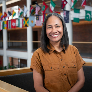 An Indigenous Fijian woman in a brown shirt, with long brown and grew hair smiles at the camera
